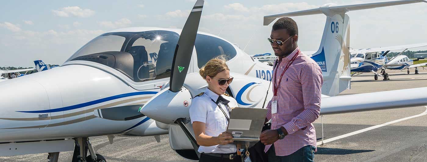 Student pilot and instructor pilot stand side by side and review clipboard