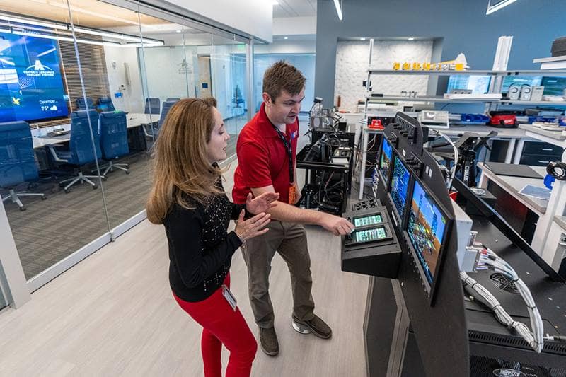 A man and a woman looking at avionics hardware in a lab.