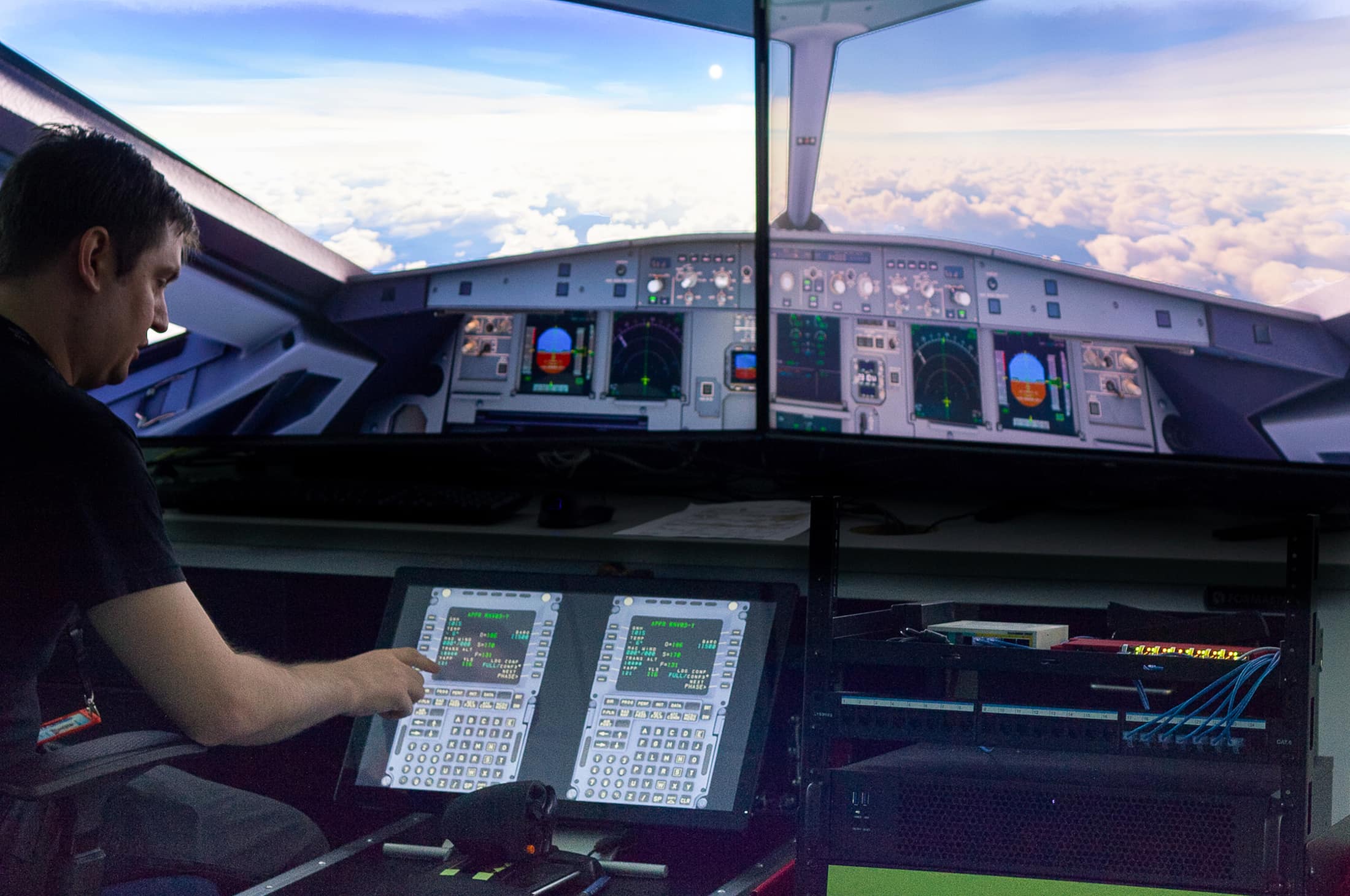 Jake Neighbors, software engineer, points to a simulated flight management system computer in Embry‑Riddle’s CARS lab, part of the virtual aircraft architecture being developed by CARS for the FAA to enhance aviation cybersecurity. 