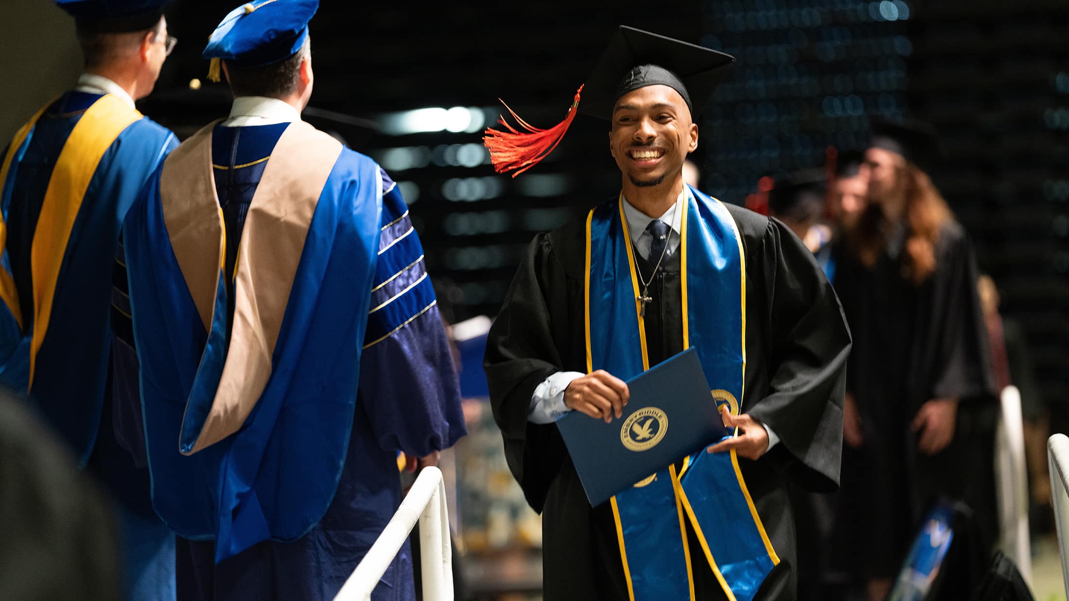 Photo of graduate crossing the stage holding his diploma.