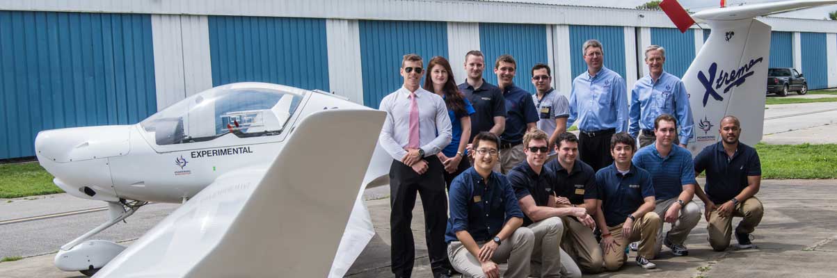 Students and faculty stand in front of a plane.