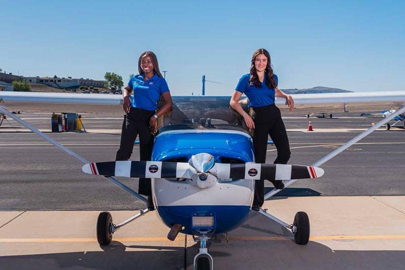 Female pilots stand next to Cessna plane