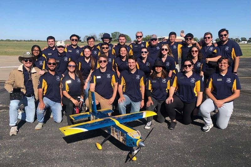 DBF team gathers with their designed aircraft in front of them