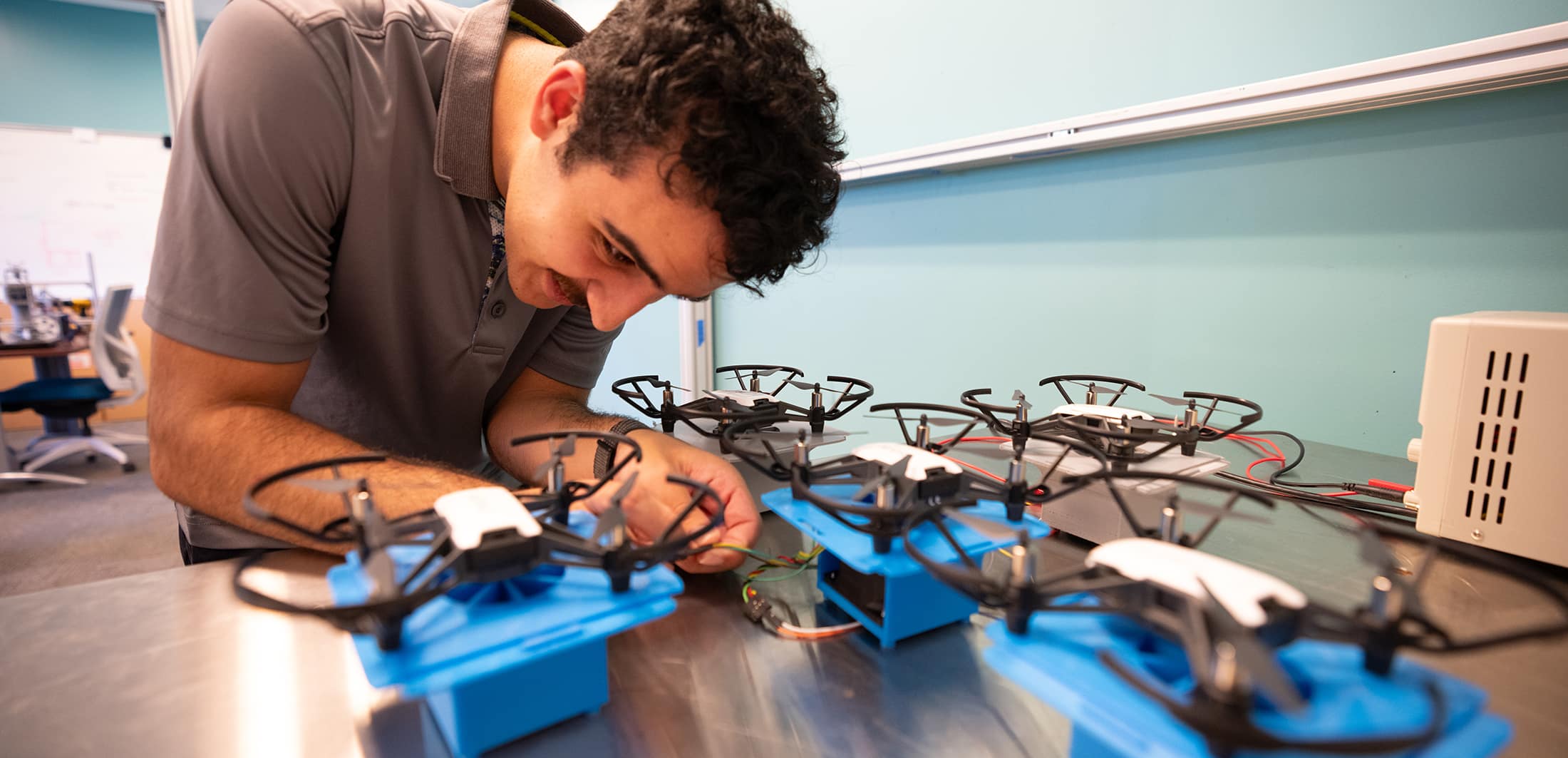 A student works on small drones at a table.