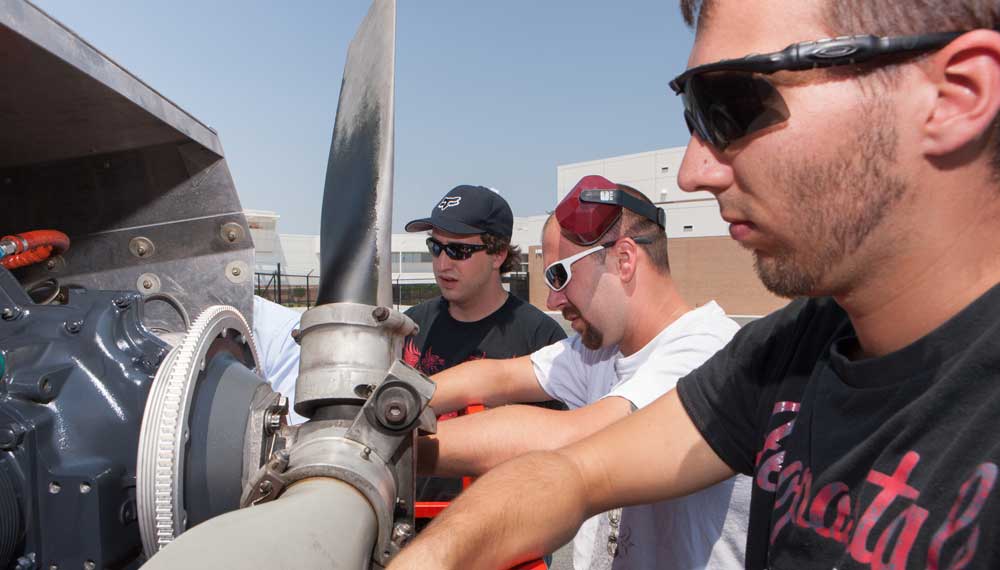 Students work on a plane's propeller.