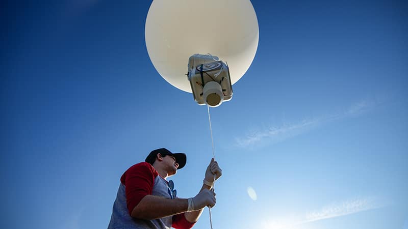 Student holds weather balloon.