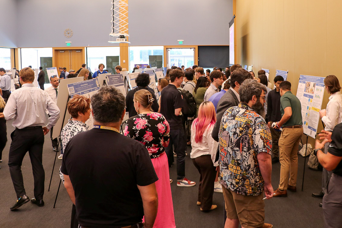 Dozens of people in a room with research posters