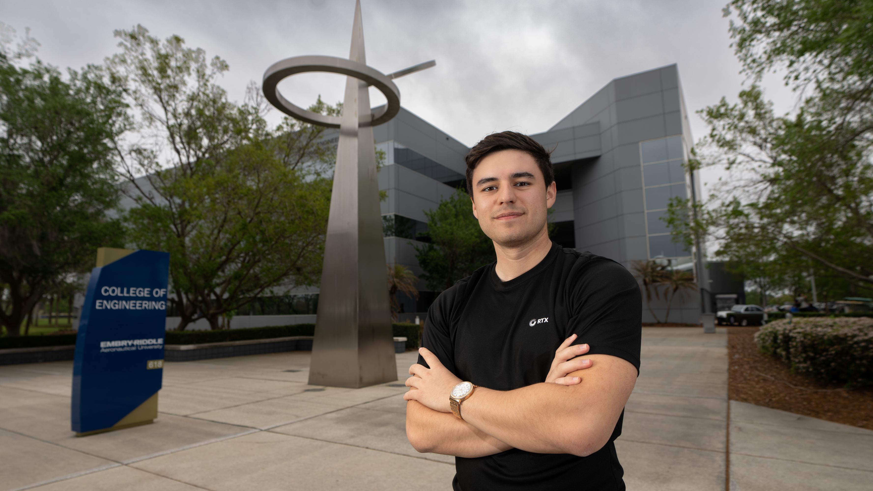 Man in front of building with sign and statue 